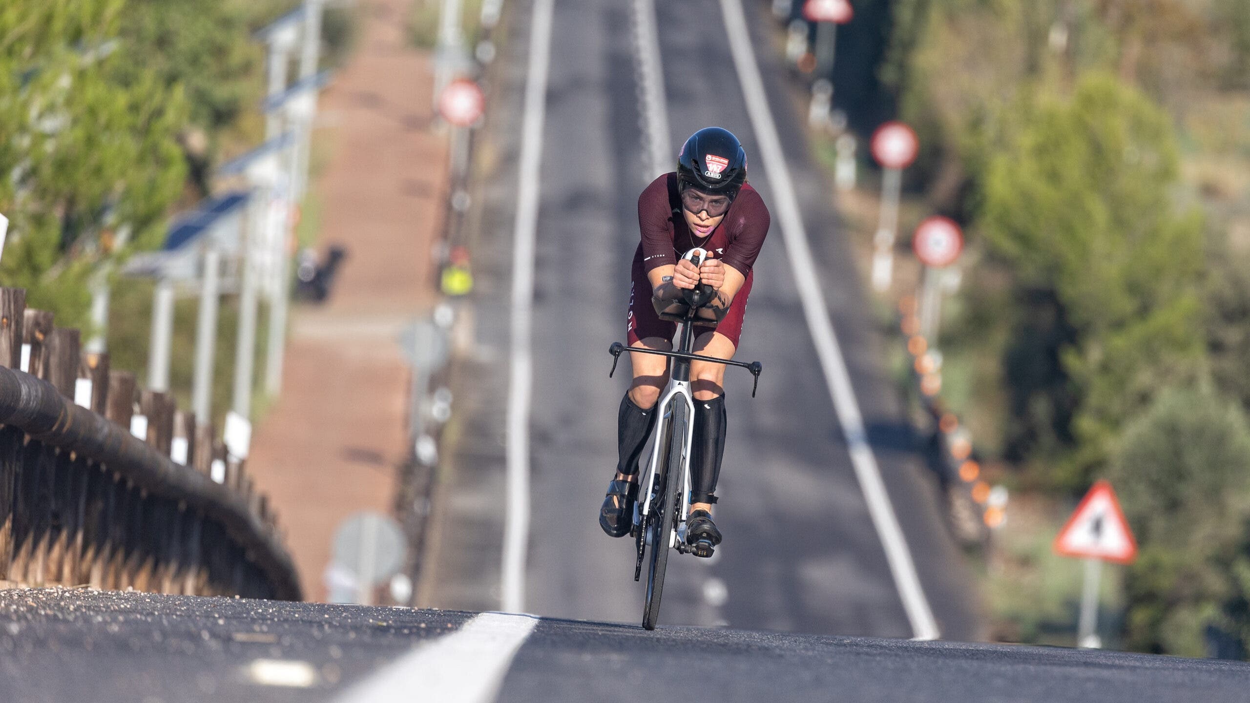 A triathlete climbs a hill after gaining strength and endurance using a muscular endurance workout on a bike.