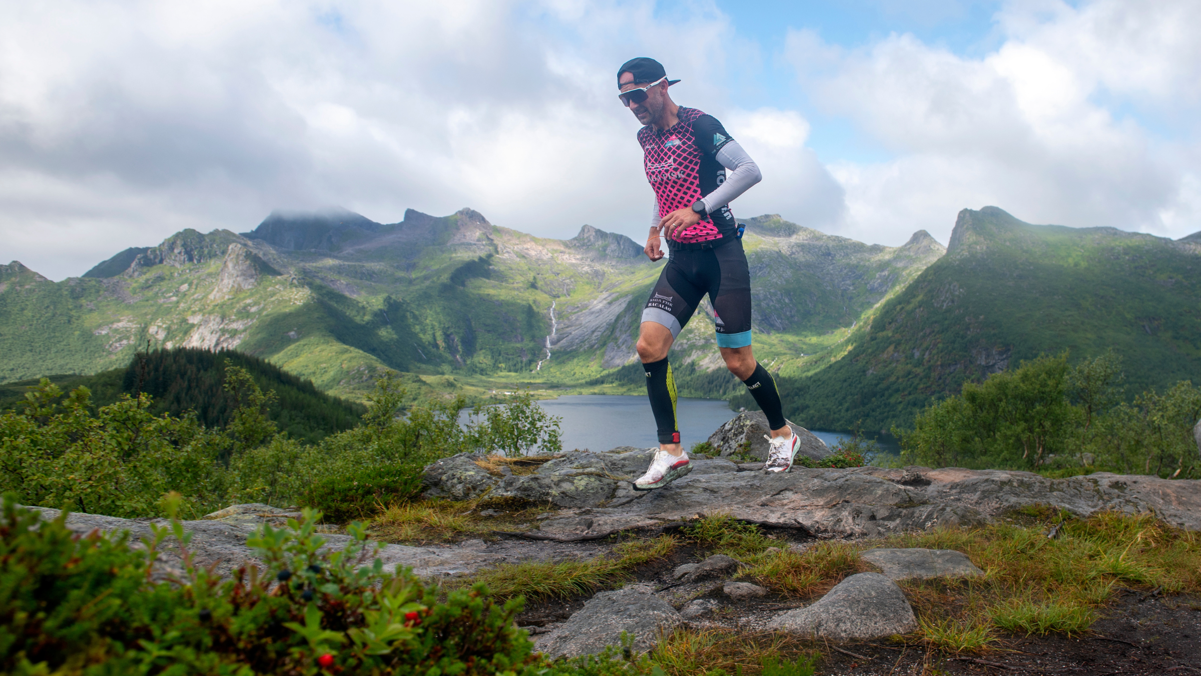 Man in triathlon suit running on road with mountains in background, Lofoten Triathlon