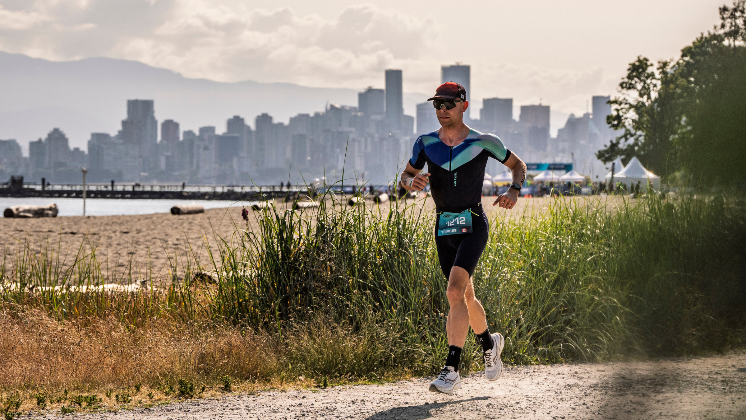 Man running in triathlon suit on road with Vancouver skyline in background, Vancouver T100