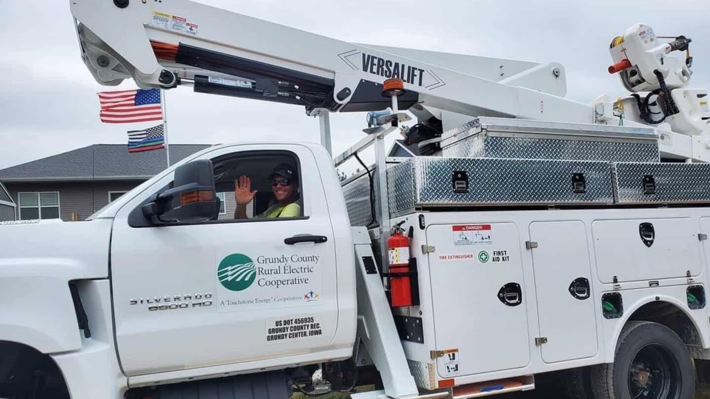 A man waves from a white work truck designated to service power lines