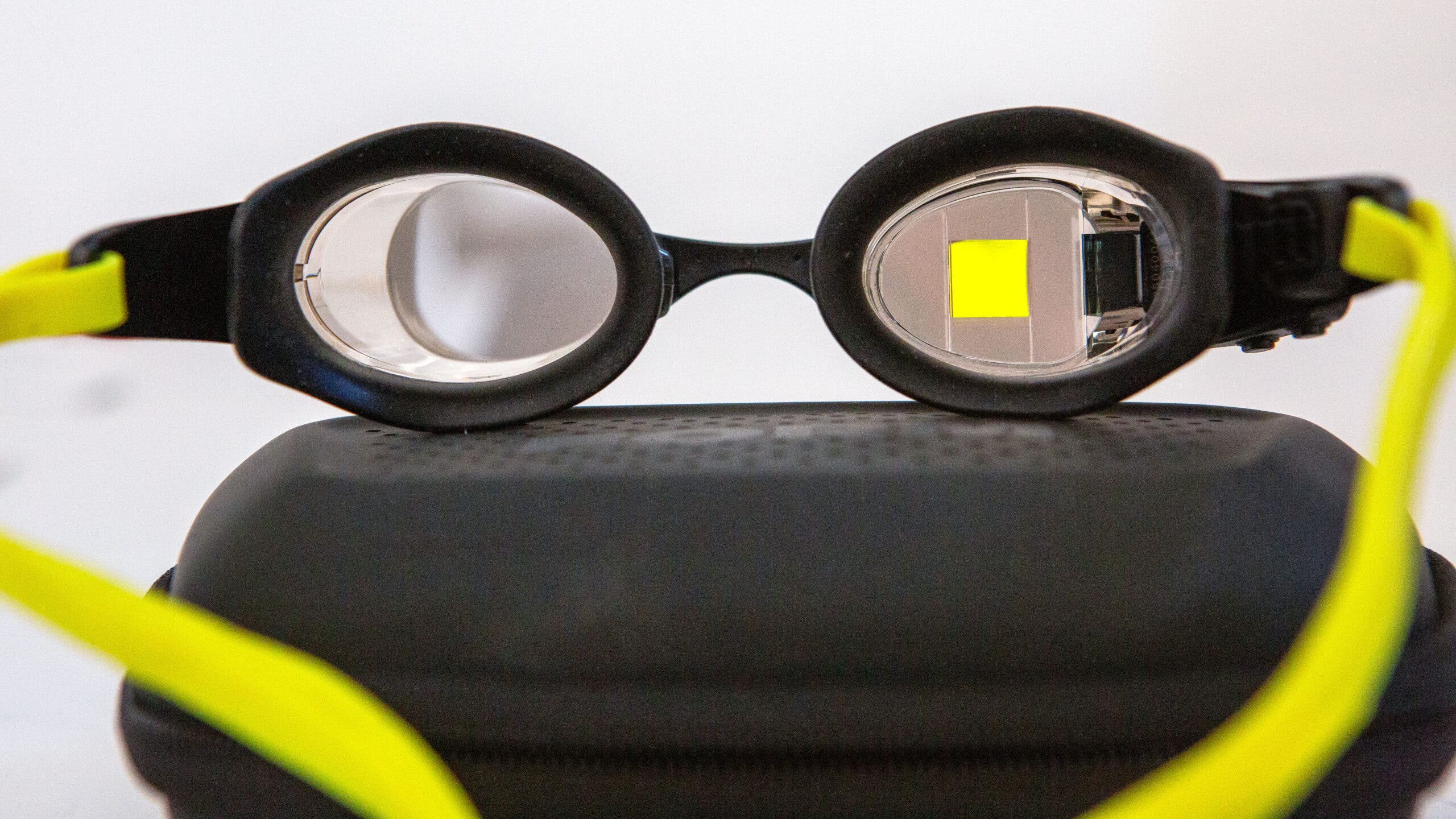 Swim Smart Form 2 LT goggles with black frame and bright yellow straps sitting on top of black case with yellow square displayed on right lens