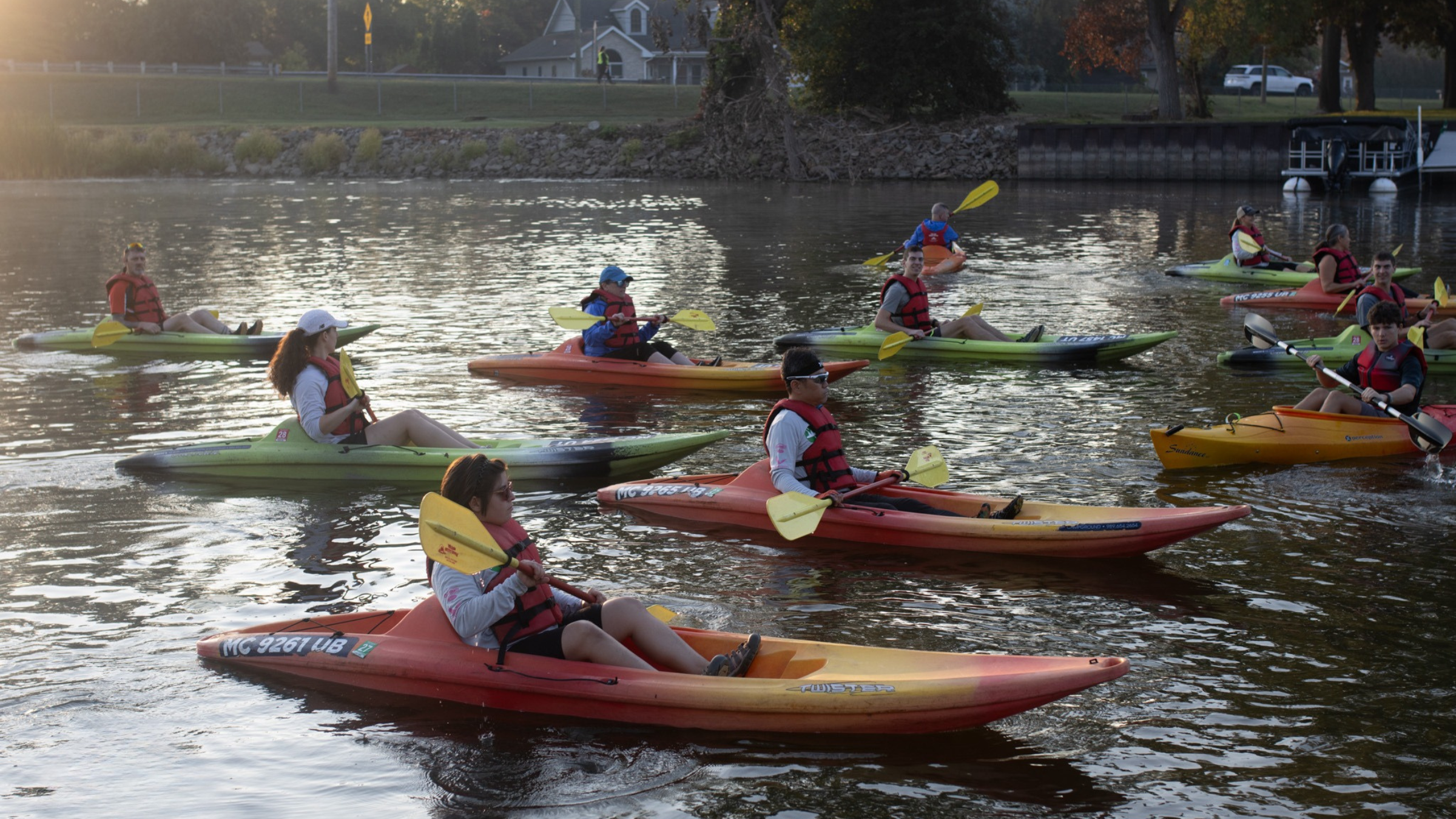 multiple kayakers sit in the water with their paddles at the Bay City Morning Rotary Driathlon race
