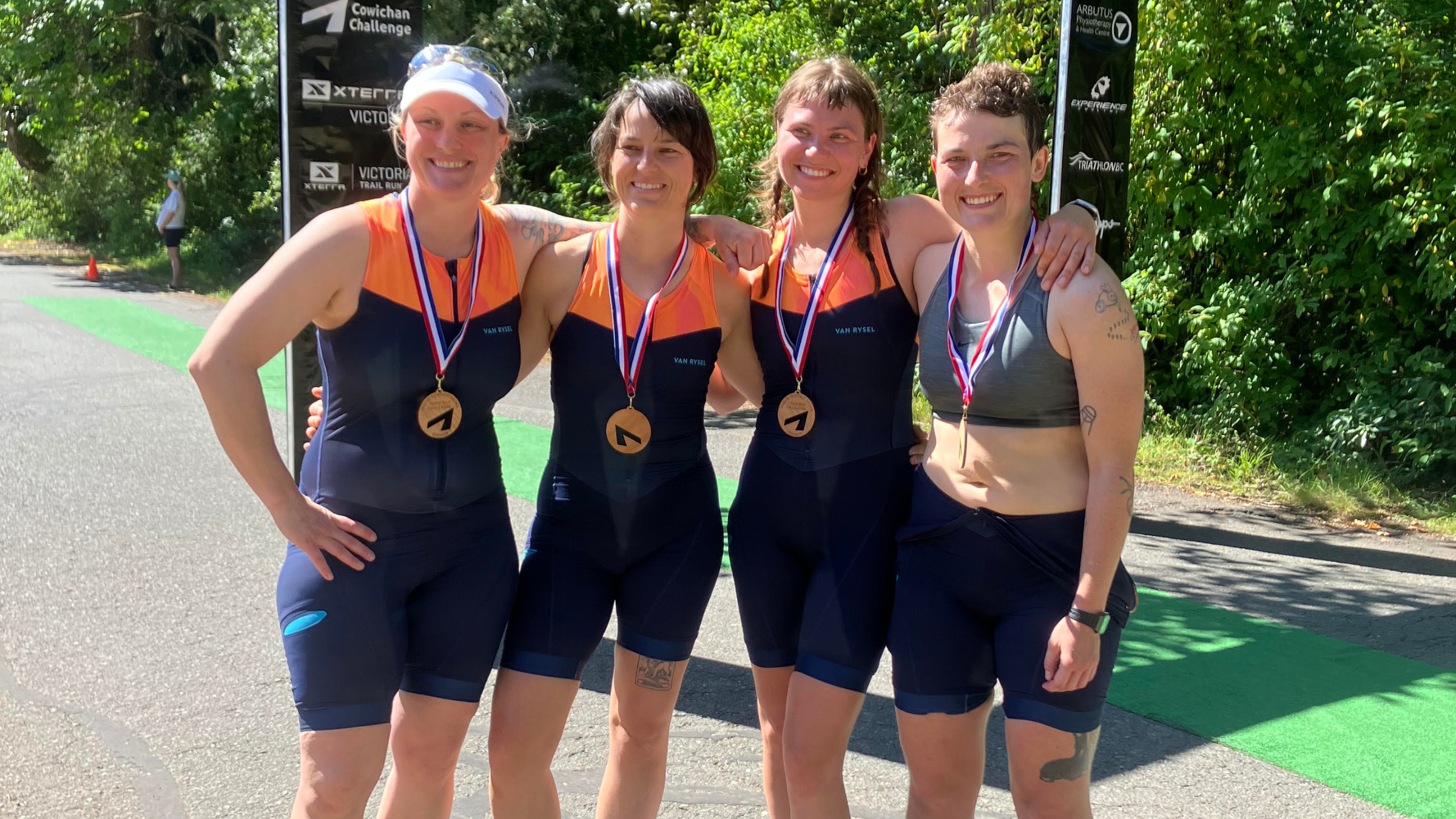 four women stand with arms around each other after a sprint triathlon